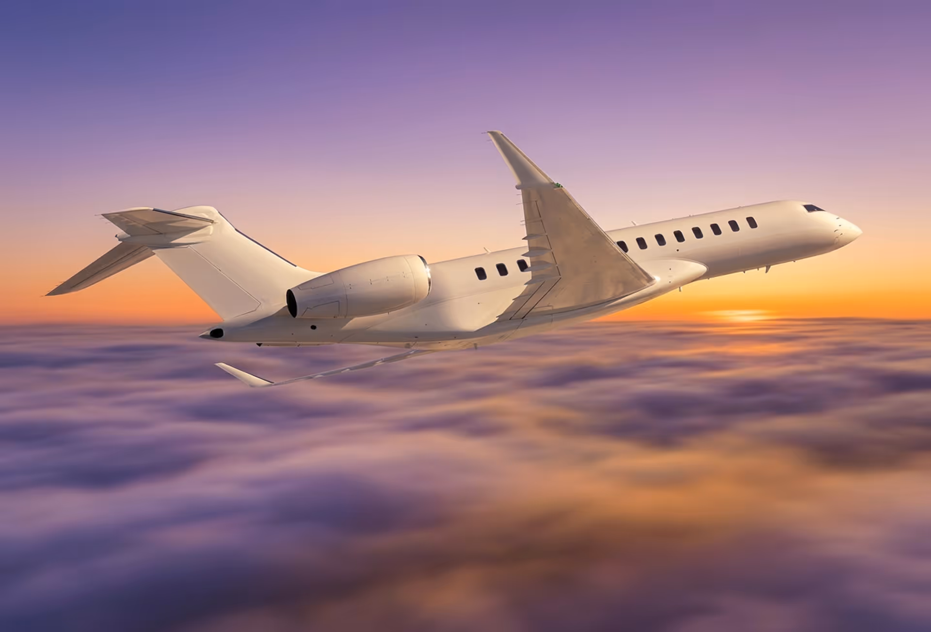 Private jet flying above purple and orange clouds during sunset.