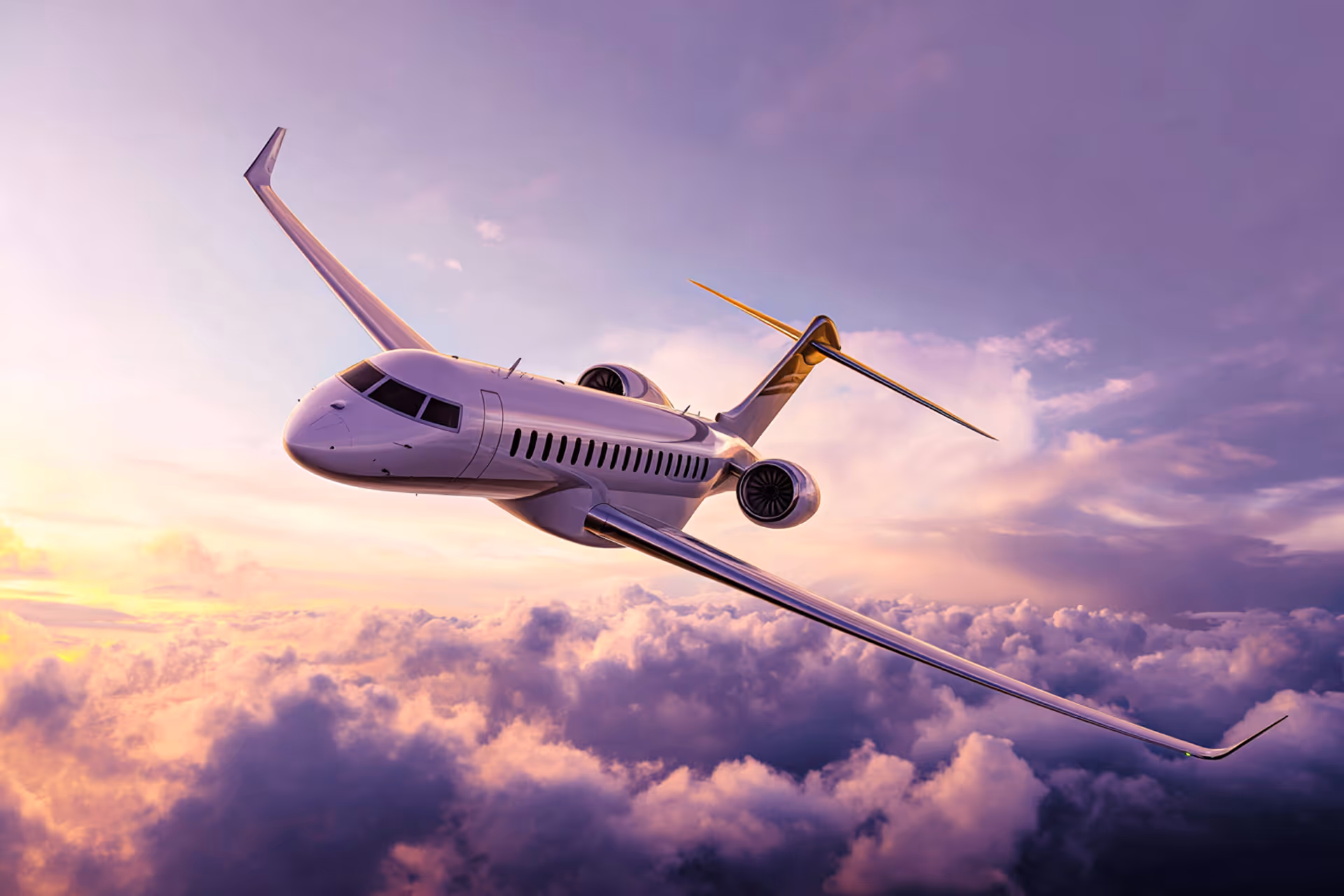 Private jet flying above purple and orange clouds during sunset.