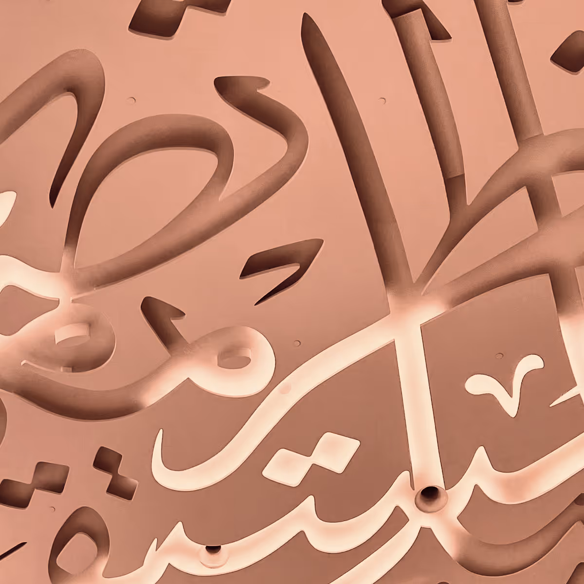 Close-up of a ceiling with abstract Arabic calligraphy cutouts illuminated from behind.