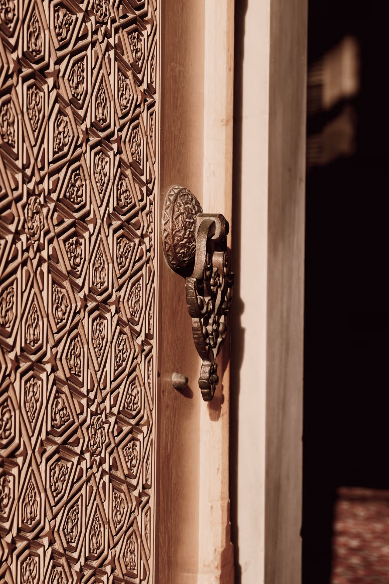 Close-up of an intricately carved wooden door with geometric patterns and a decorative metal door knocker.