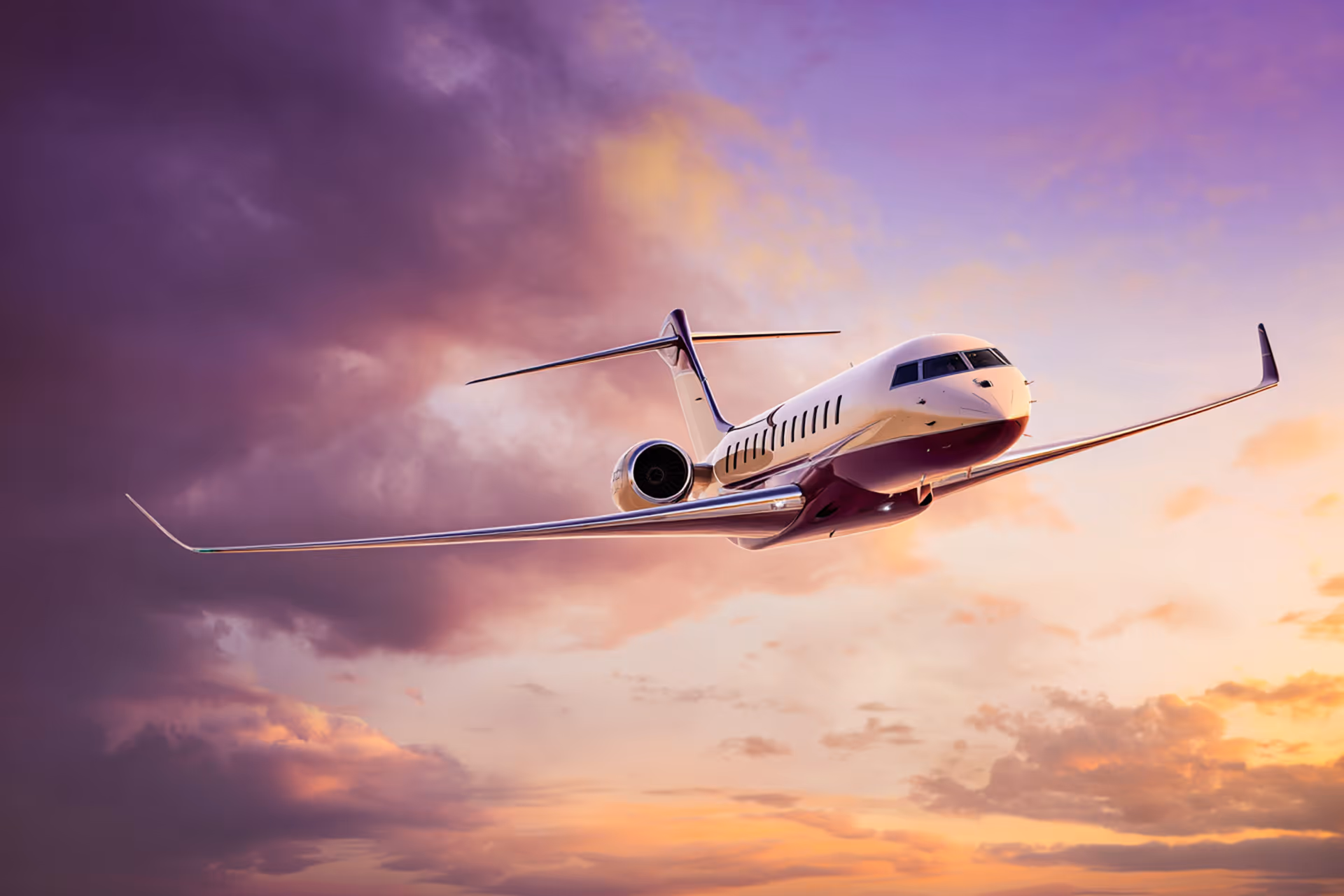 Private jet flying against a dramatic sunset sky with purple and orange clouds.
