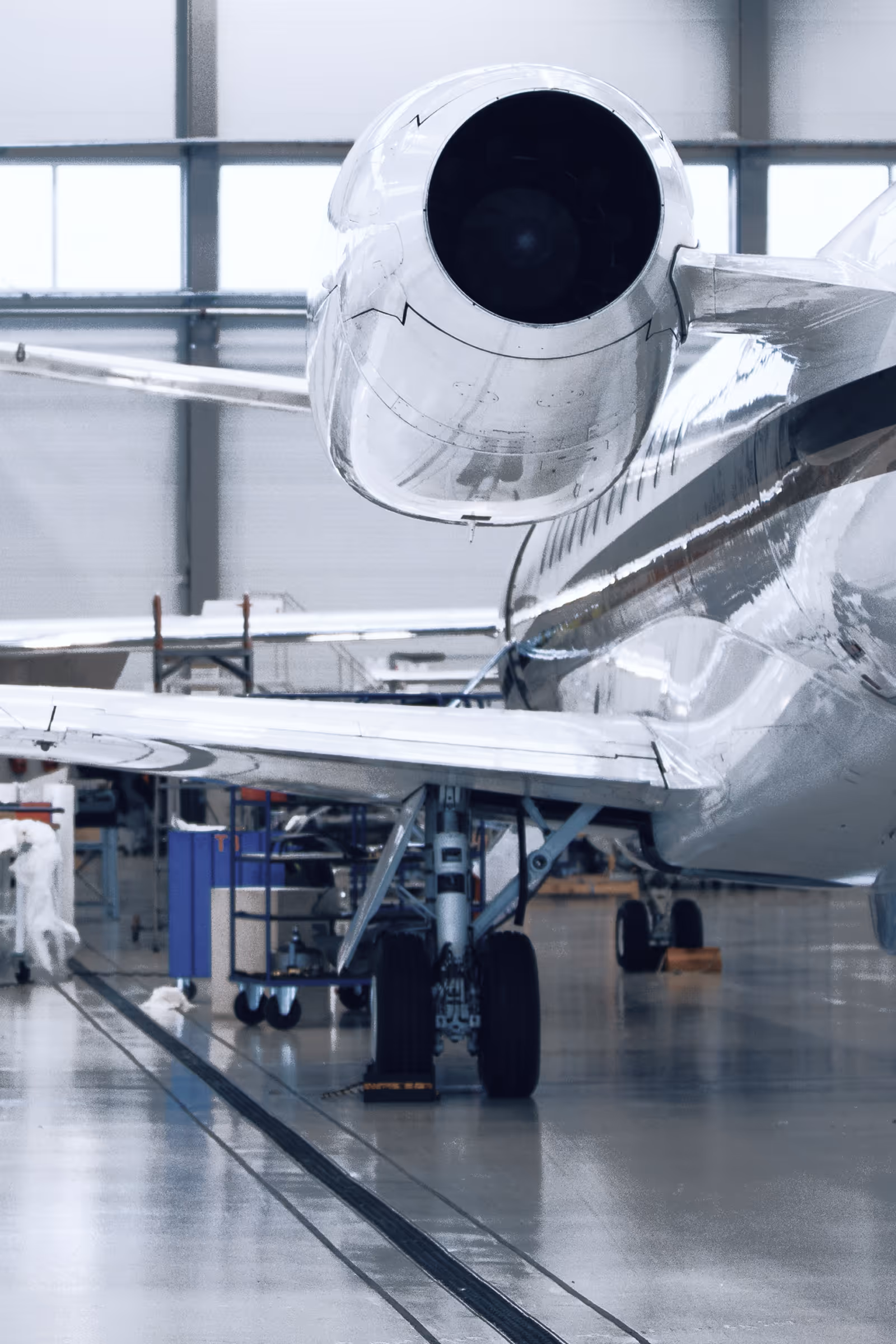 Close-up rear view of a jet engine mounted on the tail of a private jet inside an aircraft hangar.